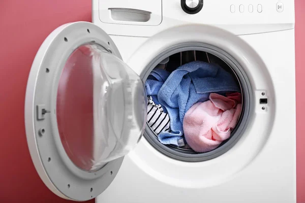 Modern washing machine with laundry on color background — Stock Photo, Image