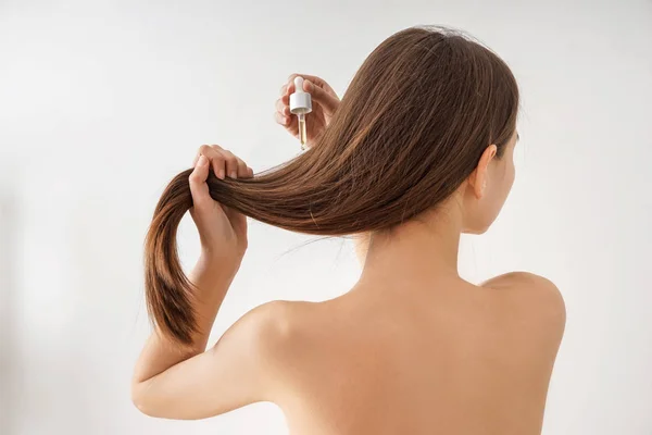 Frau verwendet Kosmetik zur Haarpflege auf weißem Hintergrund — Stockfoto