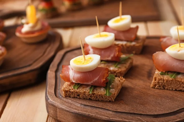 Tasty canapes on wooden board, closeup — Stock Photo, Image