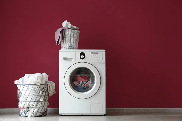 Moderna tvättmaskin och tvätt nära färg vägg — Stockfoto