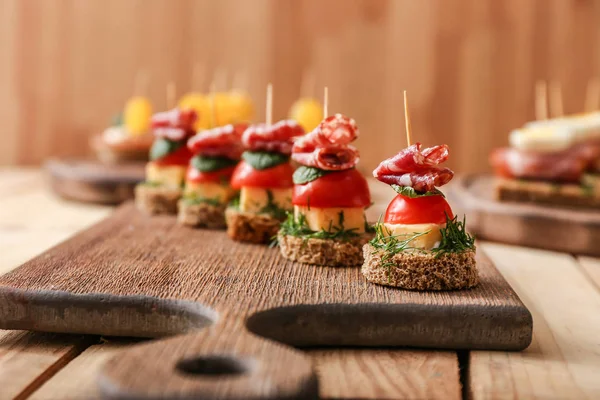 Sabrosos canapés sobre tabla de madera, primer plano —  Fotos de Stock