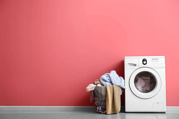 Modern washing machine and laundry near color wall — Stock Photo, Image