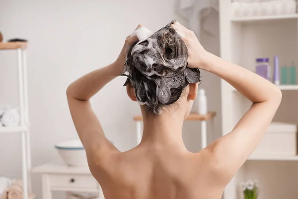 Jovem mulher lavando o cabelo no banheiro — Fotografia de Stock