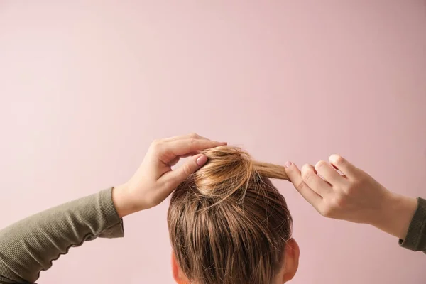 Giovane donna che fa i capelli su sfondo di colore — Foto Stock