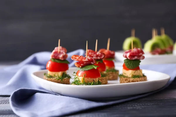 Plate with tasty canapes on wooden table — Stock Photo, Image