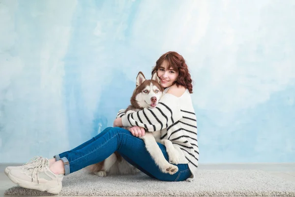 Young woman with her cute dog near color wall — Stock Photo, Image