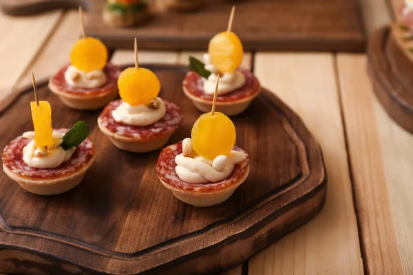 Tasty canapes on wooden board — Stock Photo, Image
