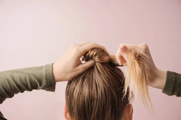 Mujer joven haciendo pelo sobre fondo de color — Foto de Stock