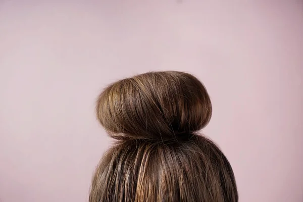 Mladá žena s vlasy drdol na barvu pozadí — Stock fotografie