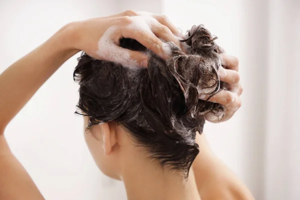 Νεαρή γυναίκα το πλύσιμο των μαλλιών στο μπάνιο — Φωτογραφία Αρχείου