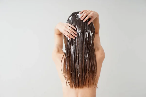 Kobieta za pomocą olej kokosowy do włosów na białym tle — Zdjęcie stockowe