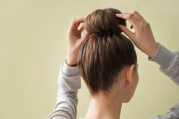 Young woman with hair bun on color background