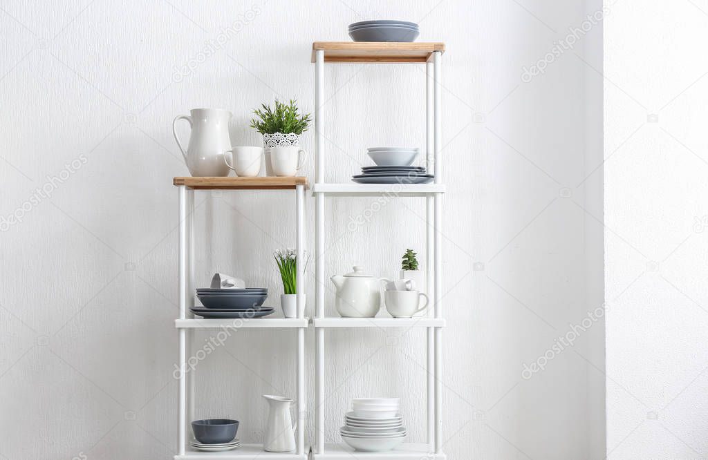 Rack with clean dishes near white wall in kitchen