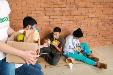 Tuğla duvara yakın oturan zavallı insanlar yiyecek veren gönüllüler