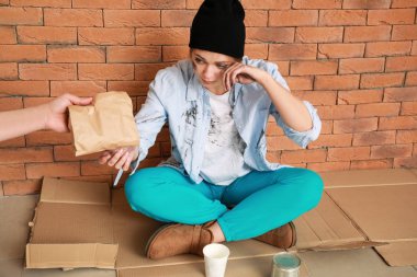 Tuğla duvara yakın oturan zavallı kadın için gönüllü veren gıda