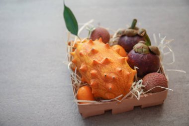 Gri arka planda lezzetli egzotik meyveler çeşitleri ile kutu
