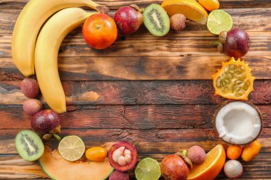 Ahşap arka planda lezzetli egzotik meyvelerden yapılmış çerçeve