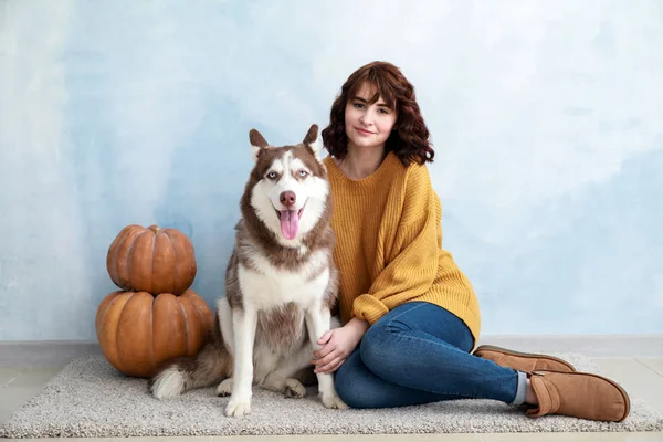 Young woman with her cute dog near color wall — Stock Photo, Image