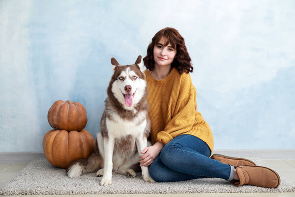 Young woman with her cute dog near color wall