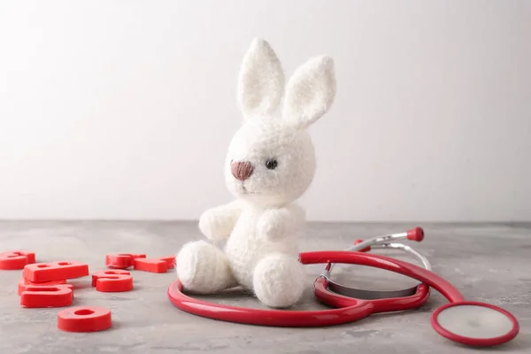 Cute bunny toy with stethoscope on grey table. Health care for kids — Stock Photo, Image