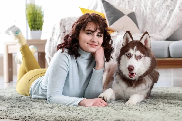 Young woman with her cute dog lying on carpet at home — Stock Photo, Image