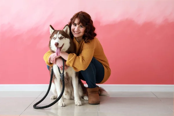 Young woman with her cute dog near color wall — Stock Photo, Image