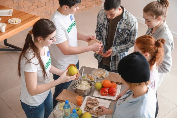 Young volunteers giving food to poor people