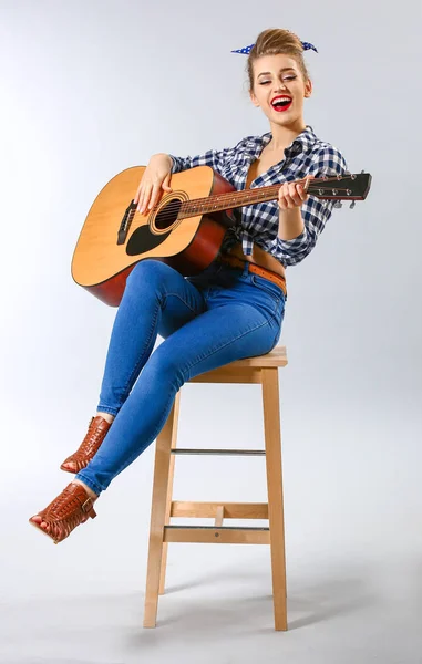 Mooie vrouw van de pin-up met gitaar op grijze achtergrond — Stockfoto