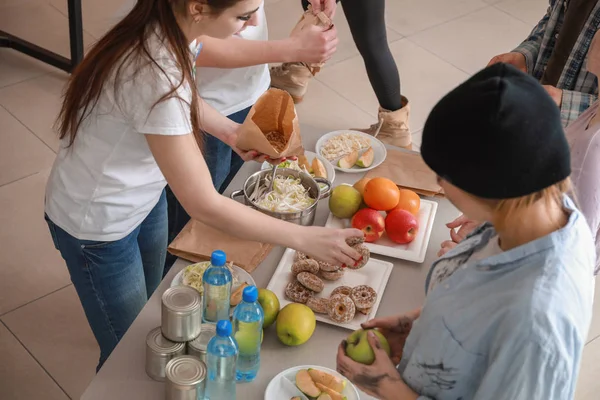 Jóvenes voluntarios dando comida a los pobres — Foto de Stock