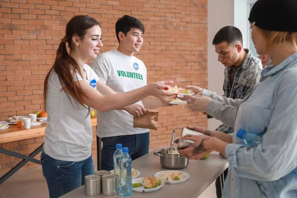 Jóvenes voluntarios dando comida a los pobres —  Fotos de Stock