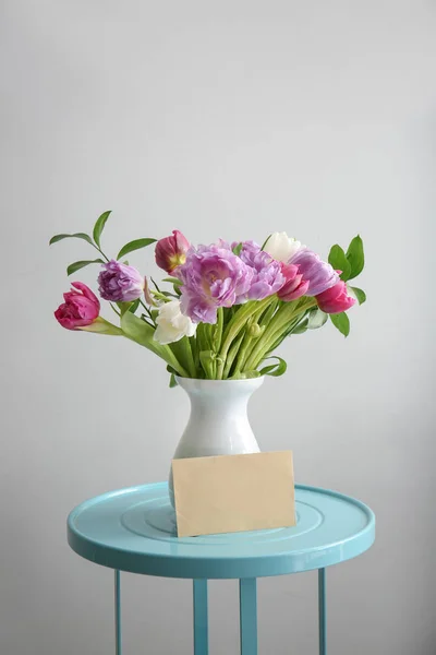 Букет красивих квітів з листівкою на столі на сірому фоні — стокове фото