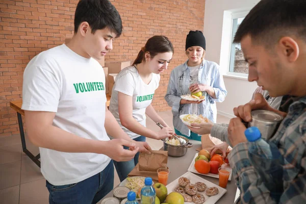 Young volunteers giving food to poor people — Stock Photo, Image