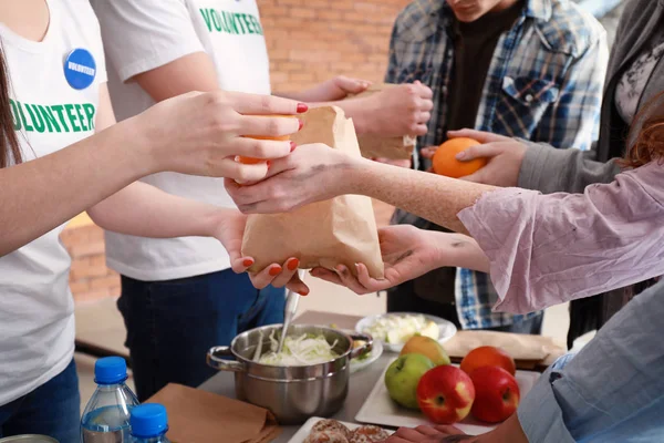 Jóvenes voluntarios dando comida a los pobres — Foto de Stock