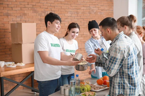 Jóvenes voluntarios dando comida a los pobres — Foto de Stock