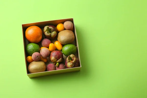 Box with assortment of tasty exotic fruits on color background