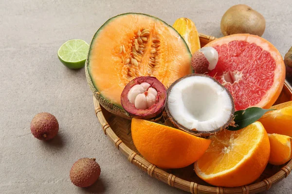 Plate with assortment of tasty exotic fruits on grey table — Stock Photo, Image