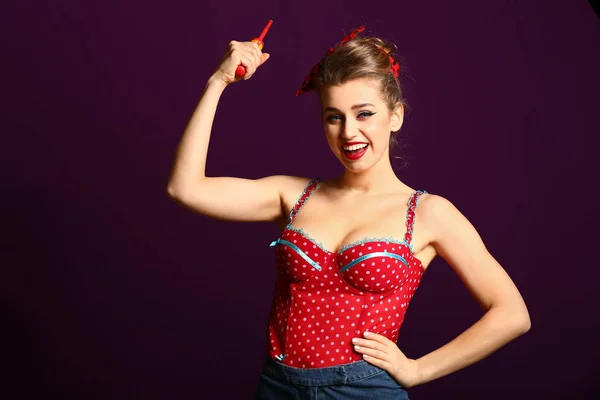 Beautiful pin-up woman with screwdriver showing muscles on color background — Stock Photo, Image