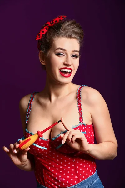 Beautiful pin-up woman with screwdriver on color background — Stock Photo, Image