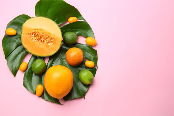 Ассортимент вкусных экзотических фруктов с тропическим листом на цветном фоне
