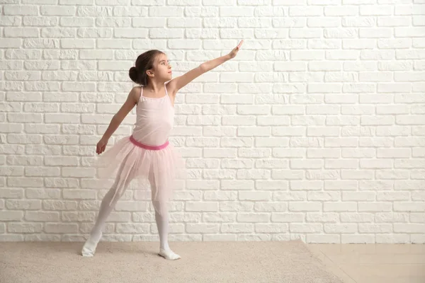 Beyaz tuğla duvar yakınındaki küçük şirin balerin — Stok fotoğraf