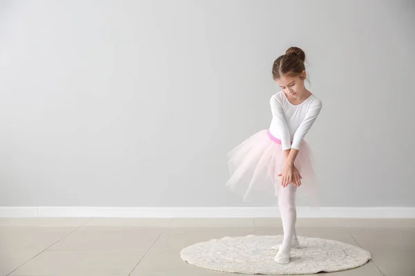Cute little ballerina dancing near light wall — Stock Photo, Image