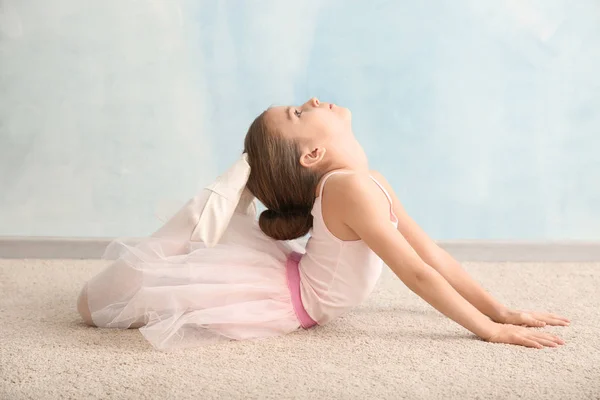 Niedliche kleine Ballerina dehnt sich in der Nähe von Lichtwand — Stockfoto