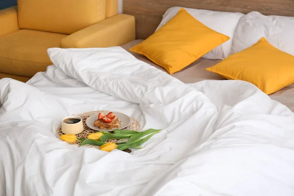 Tasty healthy breakfast and flowers on bed — Stock Photo, Image