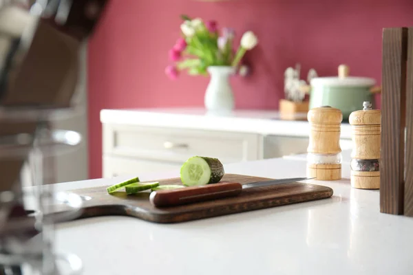 Placa de corte com pepino fresco e faca na mesa na cozinha — Fotografia de Stock