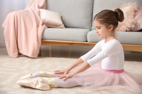 Schattige kleine ballerina zittend op tapijt thuis — Stockfoto