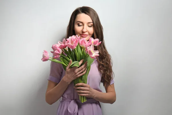 Buket çiçek ışık arka plan üzerinde güzel bir kadınla — Stok fotoğraf