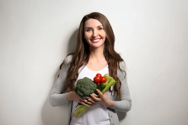 Woman with fresh vegetables on light background — Stock Photo, Image