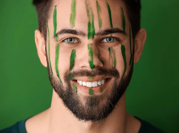 Portrait of handsome man with paint on his face against color background — Stock Photo, Image