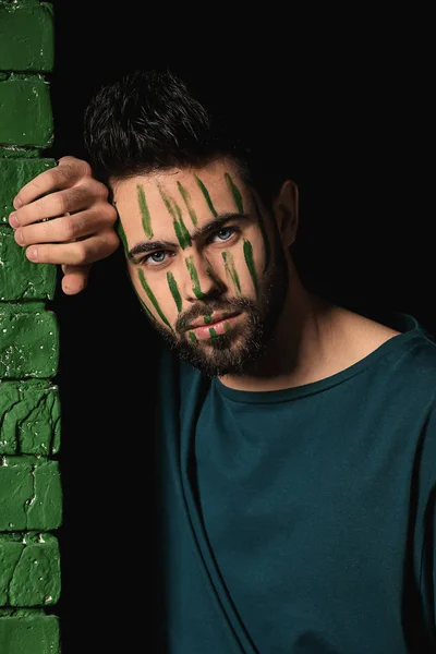 Portrait of handsome man with paint on his face near color wall — Stock Photo, Image