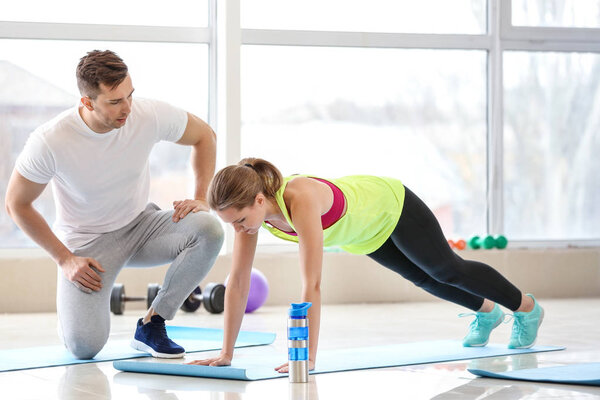 Sporty young woman training with instructor in gym
